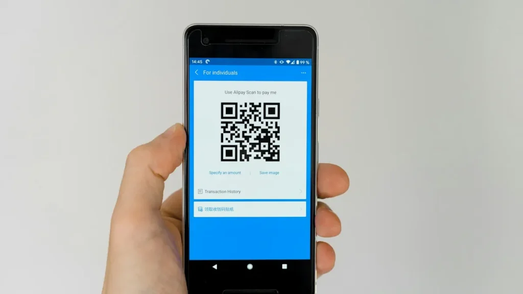 Hand holding a smartphone that shows a QR code, as used to verify an attested document online