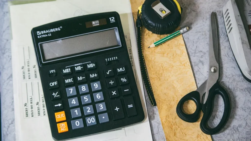 Calculator and printed documents on a desk, used to work out the cost of renewing an employee iqama