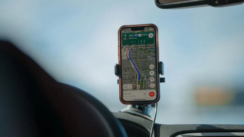 Smartphone in a dashboard holder inside a car, used to check traffic fines on Absher